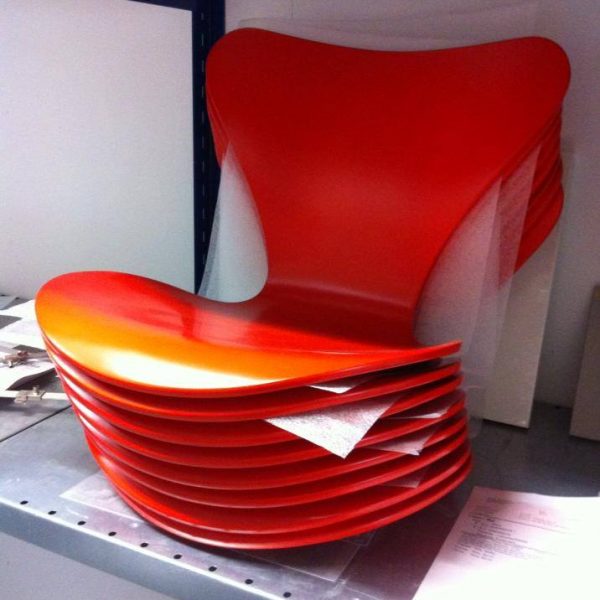 Otte nymalet Arne Jacobsen Syver-stole i orange stående på metal reol